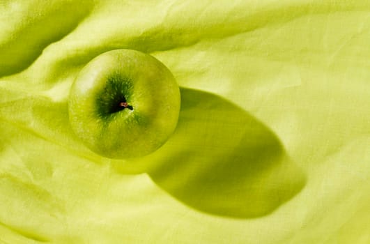 One green apple on  green cloth