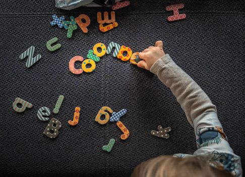 The corona menace in colorful letters from a little boy who crashes the typography with his toy car.