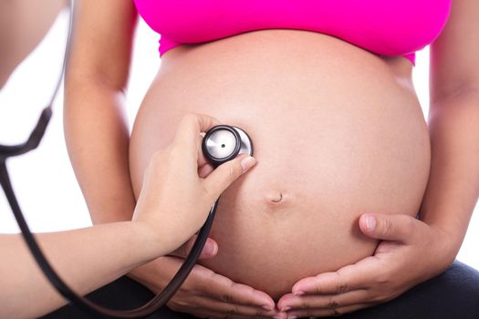 Belly closeup of a pregnant woman examined with a stethoscope