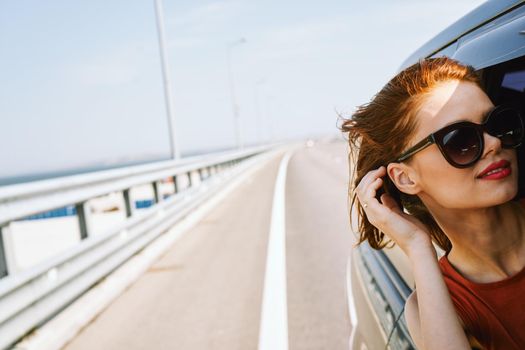 cheerful woman peeking out of the car window trip adventure lifestyle. High quality photo