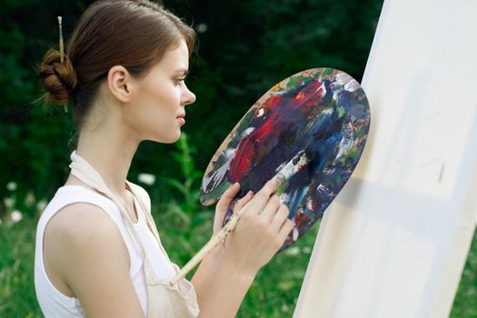 woman artist paints palette easel nature drawing. High quality photo