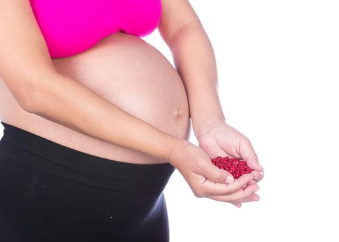 pregnant woman with red pills in her hands isolated on white background