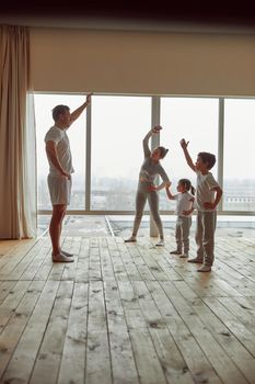Father is teaching mom with son and daughter how to exercise during quarantine in living room