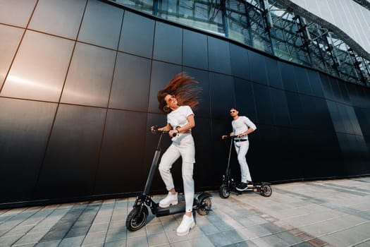 A girl and a guy are walking on electric scooters around the city, a couple in love on scooters