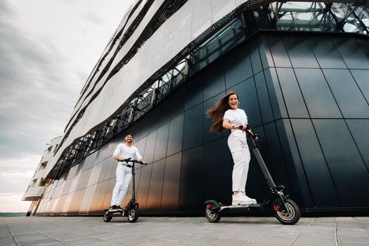 A girl and a guy are walking on electric scooters around the city, a couple in love on scooters