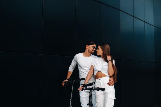 A girl and a guy are walking on electric scooters around the city, a couple in love on scooters