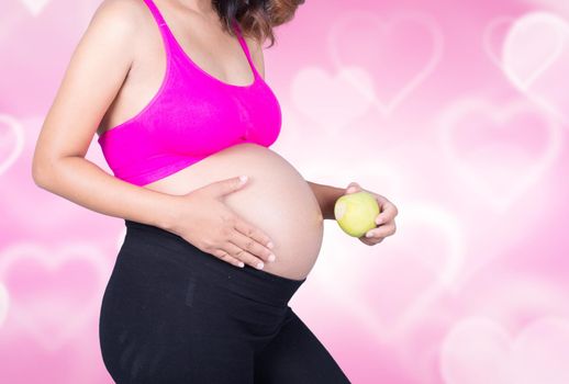 Beautiful pregnant woman with green apple on heart backrground