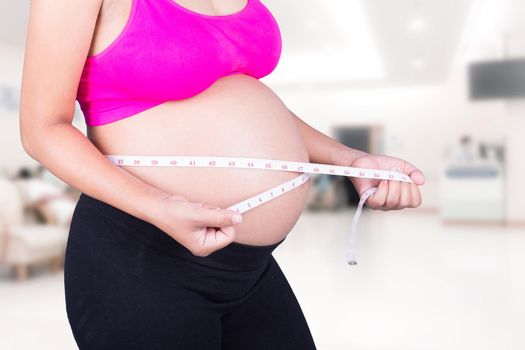 close-up belly of Pregnant woman with measuring tape in hospital background