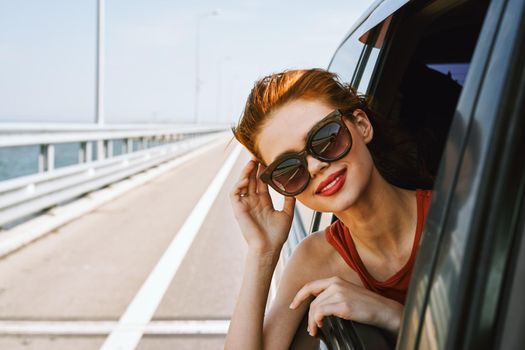 a woman is driving in a car on the road and looking out of the window. High quality photo