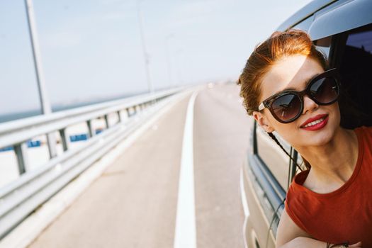 cheerful woman peeking out of the car window trip adventure lifestyle. High quality photo