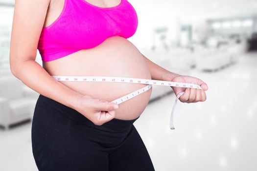 close-up belly of Pregnant woman with measuring tape in hospital background