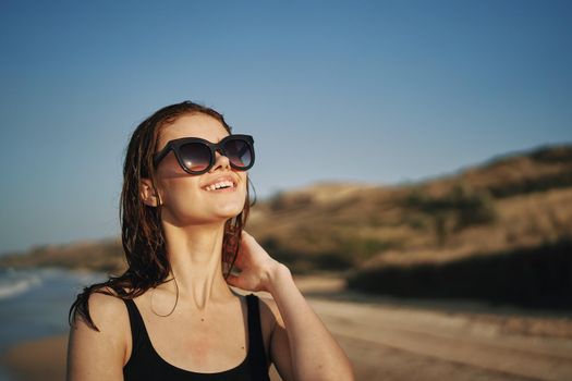 pretty woman in black swimsuit posing sun walking on the beach. High quality photo