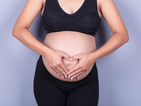 Pregnant Belly of woman with fingers Heart shape