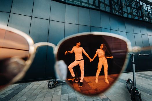 A girl and a guy are walking on electric scooters around the city, a couple in love on scooters