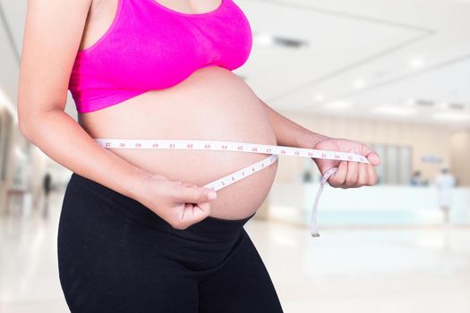 close-up belly of Pregnant woman with measuring tape in hospital background