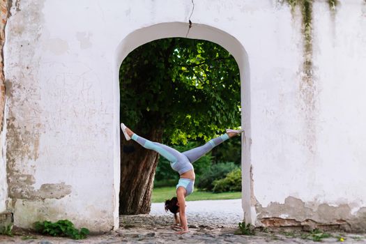 Pretty woman doing yoga exercises in the park on the ruins