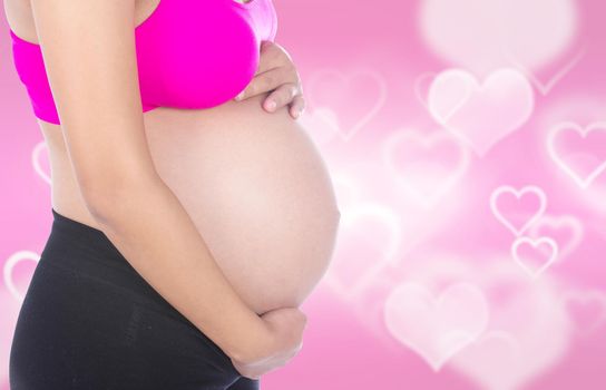 Close-up of pregnant woman belly with her hand on it isolated on heart backrground