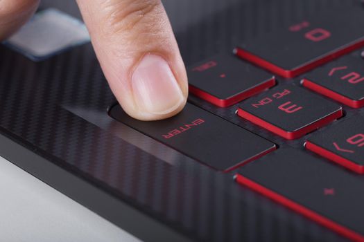 finger pushing enter button on a laptop keyboard