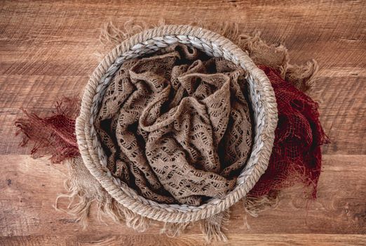 Beautiful background for newborn photosession with plants. Digital composite with knitted basket filled with colorful fabric and standing on sackcloth