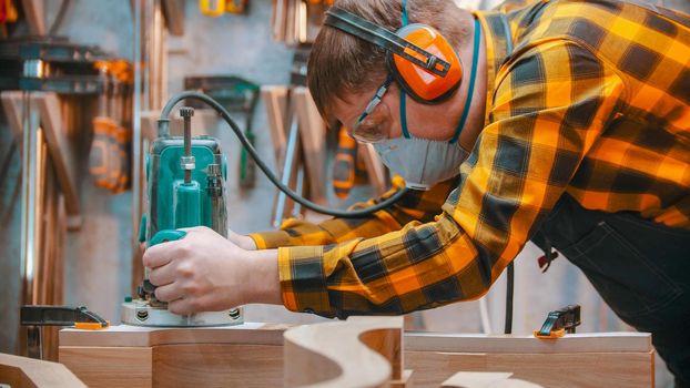 Carpentry indoors - a woodworker polishes the wooden detail with an effort in the workshop. Mid shot