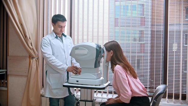 Ophthalmology treatment - young woman checking her visual acuity with a special equipment. Mid shot