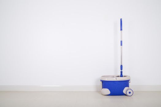 mop and blue bucket on the floor and wall background