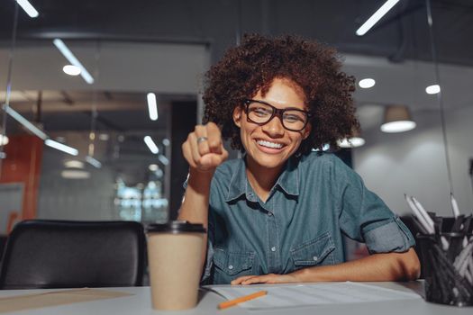 Happy young businesswoman working in the office and showing sign language