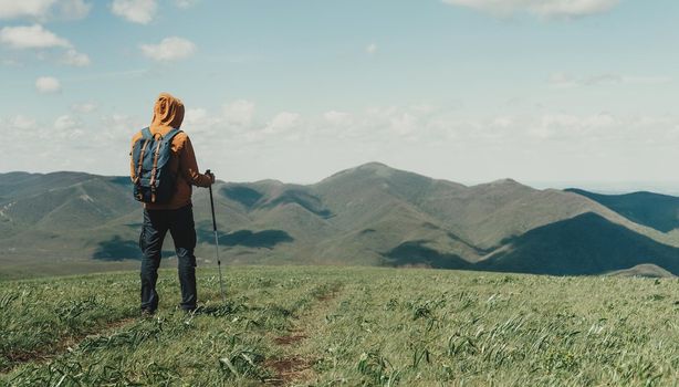 Hiker young man walking with trekking poles in the mountains