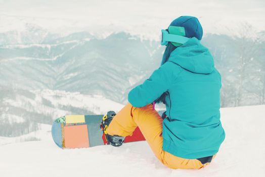 Young woman snowboarder looking at mountains in winter on ski resort