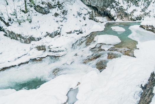 Mountain river flowing among snow banks