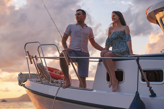 Beautiful loving couple looking at sunset from the yacht