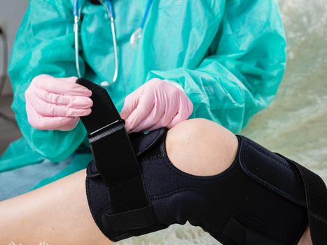 the doctor puts a bandage on the leg in the area of ​​the knee. Physiotherapy for knee injury