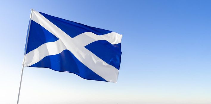 Flag of Scotland waving against clear blue sky