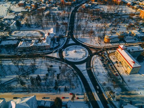 Aerial view of roundabout road with circular cars in small european city at winter sunny day. Kyiv region, Ukraine