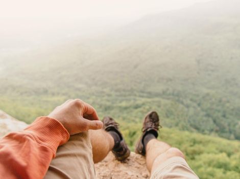 Male explorer sitting in summer mountains, point of view shot.