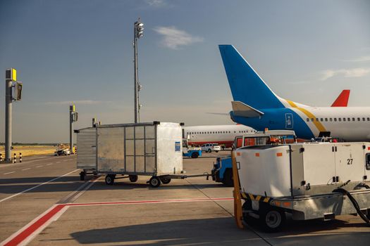 Airfield tractors near big modern airplane. Preparation of aircraft for boarding in airport hub on a daytime. Plane, shipping, transportation concept