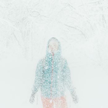 Young woman standing under falling snow in winter outdoor
