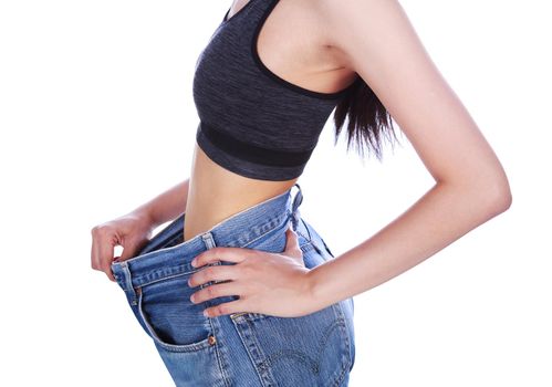 close up of woman show her weight loss and wearing her old jeans isolated on a white background