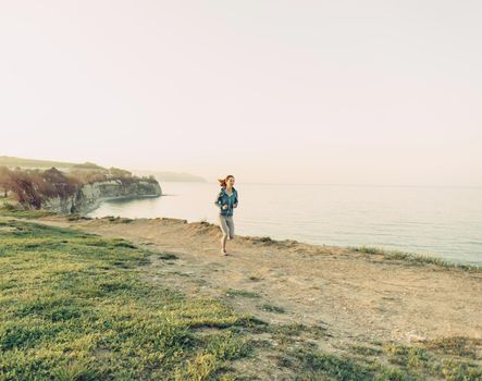 Sporty young woman running on coast near the sea in summer