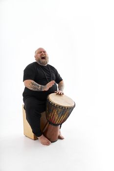 Funn caucasian bearded tattoed man is posing on white background