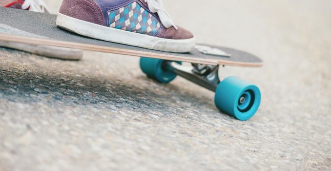 Close-up image of male leg sneakers on longboard on road.