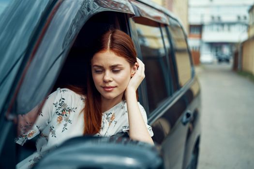 cheerful woman driving a car looks out of the window. High quality photo