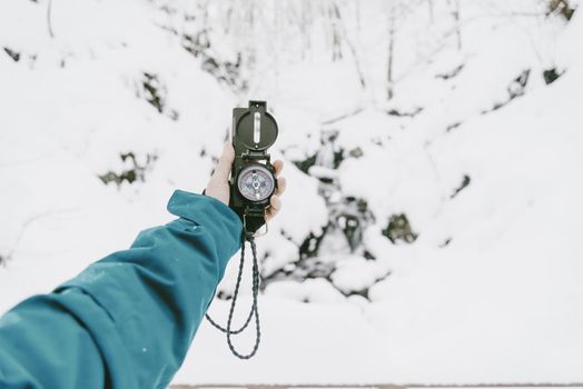 Unrecognizable female traveler searching direction with a compass in winter, point of view shot.