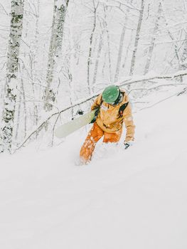 Snowboarder freerider young man walking in winter forest after snowfall