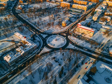 Aerial view of roundabout road with circular cars in small european city at winter sunny day. Kyiv region, Ukraine