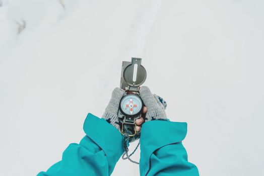 Traveler searching direction with a compass in winter outdoor. Point of view shot