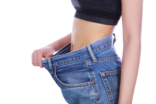 close up of woman show her weight loss and wearing her old jeans isolated on a white background