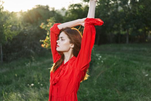 attractive woman in red dress posing in nature green grass. High quality photo