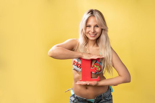 Girl holds the letters of the alphabet word love on a yellow background blonde beautiful smiles yellow concept beautiful, one little school pupil, cheerful kid. Cute copy elementary woman