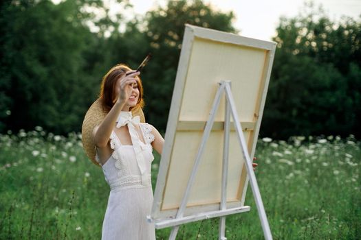 Woman in white dress paints a picture outdoors hobby creative. High quality photo